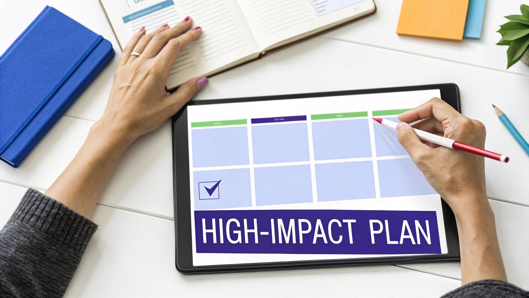 Person's hands working on a tablet displaying a 'HIGH-IMPACT PLAN' on a desk with office supplies.