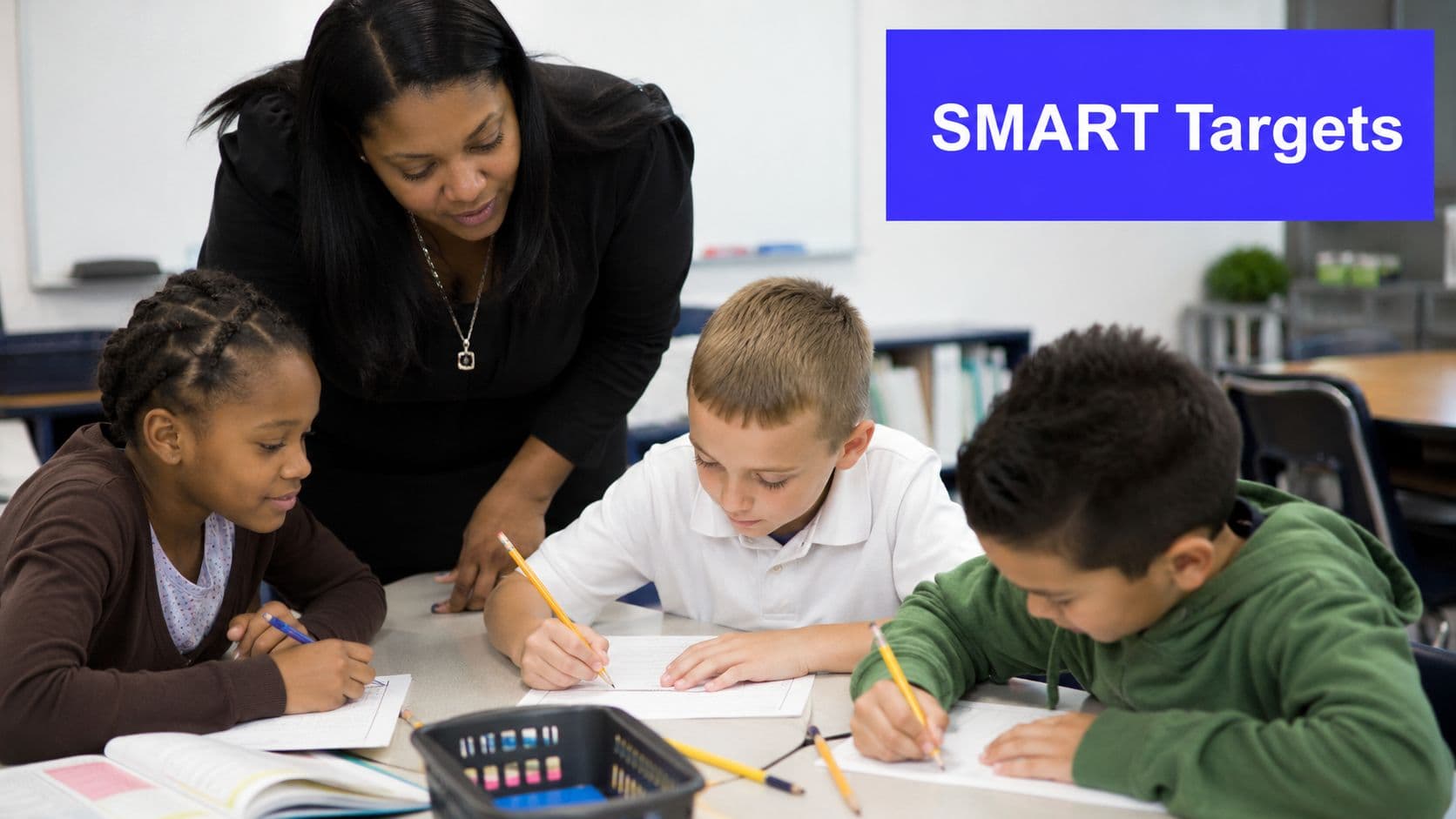 A teacher assisting three diverse elementary school students with their academic work at a classroom table.