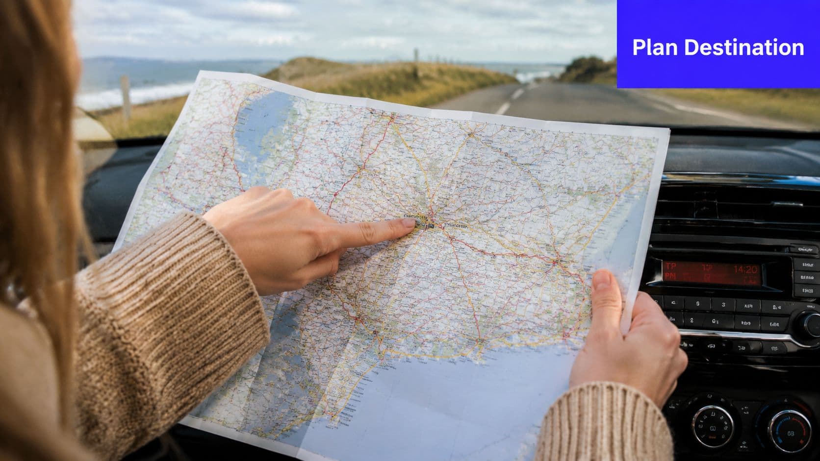 A person sitting in a car holding and pointing at a paper road map for navigation.