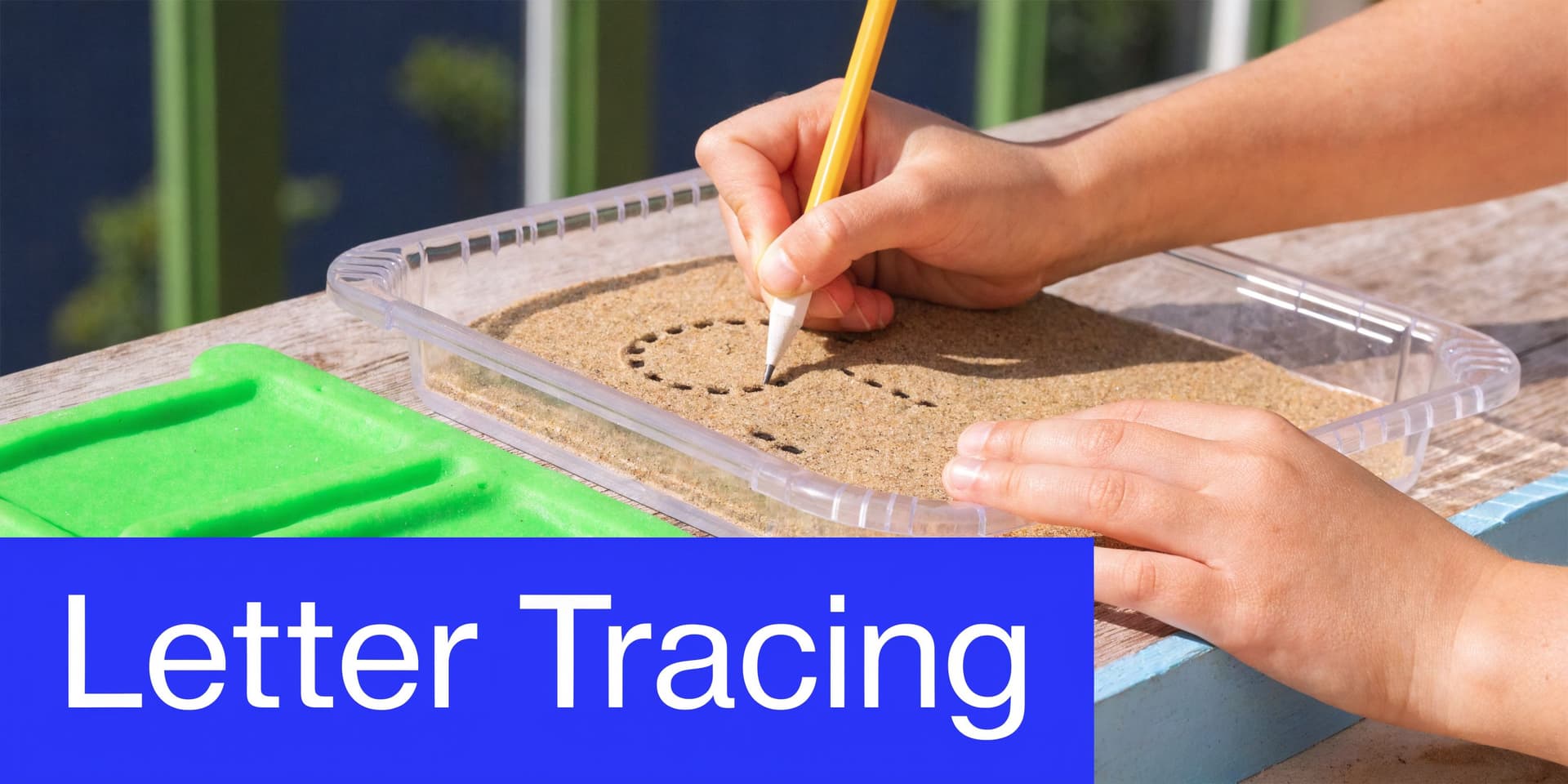 A child using a pencil to trace a letter in a sand tray for handwriting practice.