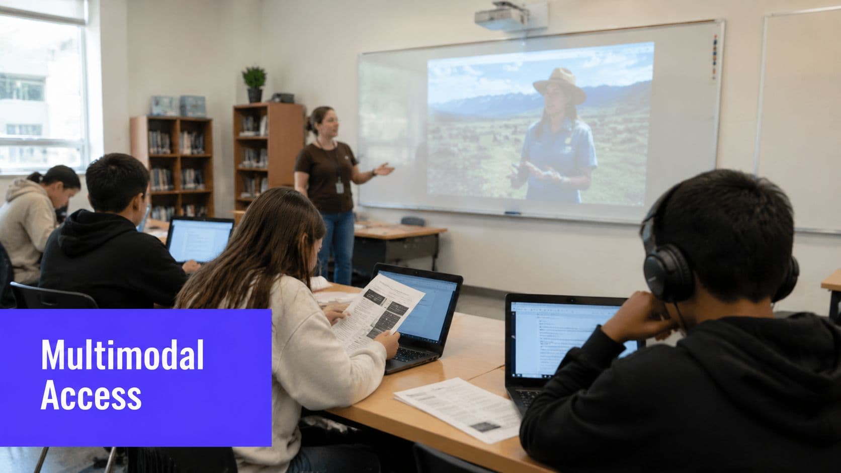 A teacher presenting in a classroom with students using laptops and headphones for learning activities.