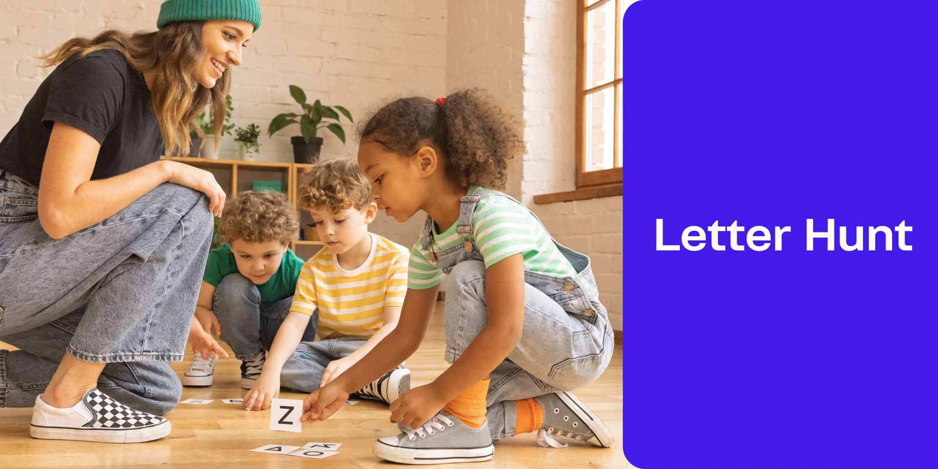 A teacher in a green beanie guides young children playing an interactive alphabet games activity on floor.