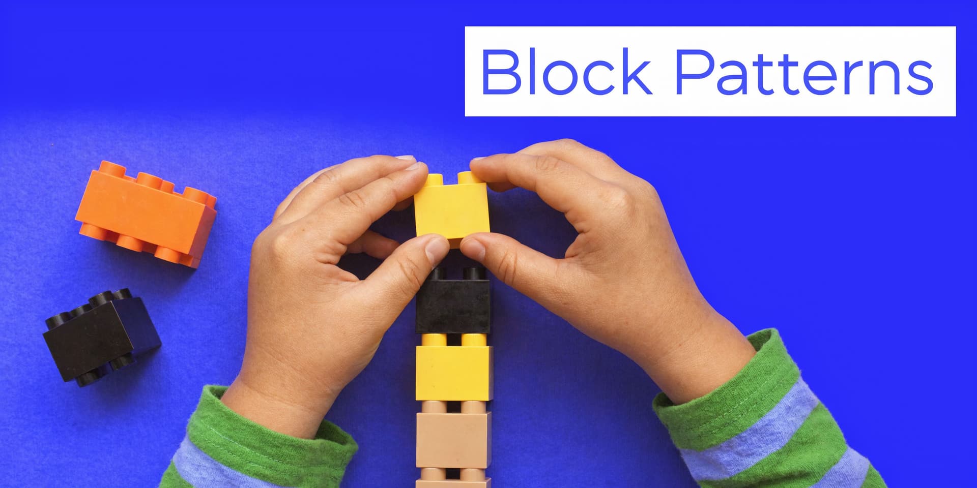 A child's hands carefully stacking colorful toy blocks in a vertical pattern on a bright blue surface.