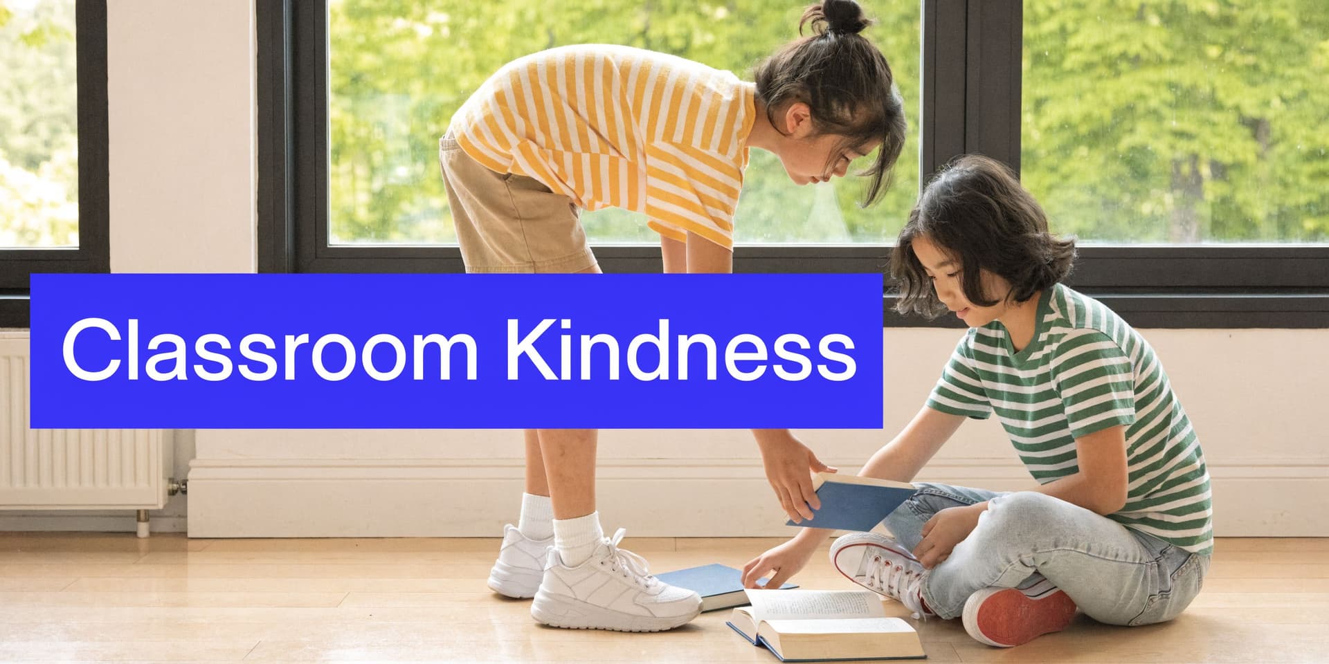 Two young Asian children sitting on a classroom floor, sharing and reading books together with kindness.