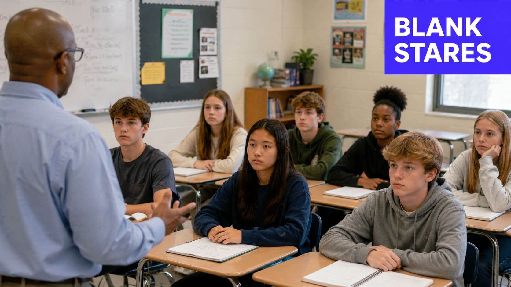 A teacher standing in a classroom while students listen attentively to his lesson at their desks.